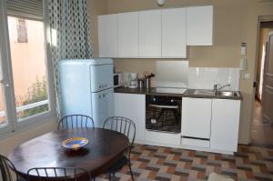 cocina con mesa de madera y nevera en Villa Maredda, en La Ciotat