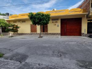 Una casa amarilla con un árbol delante. en Casa de Luna, en La Dorada