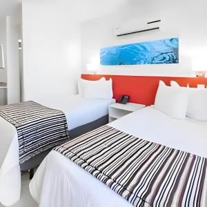 two beds in a room with white and red at True América apart-hotel in Campos dos Goytacazes