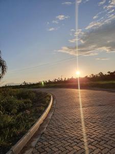 un camino de ladrillo con la puesta de sol en la distancia en Casa pedrinhas, en Ilha Comprida