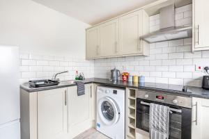 cocina con armarios blancos, lavadora y secadora en Two bedroom flat near Colchester Hospital with free parking and internet, en Mile End