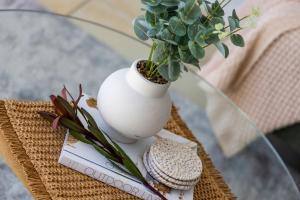 a white vase with a plant on a glass table at Sandcastles at the Beach - Linen Supplied & Beds Ready on Arrival in Fingal Bay