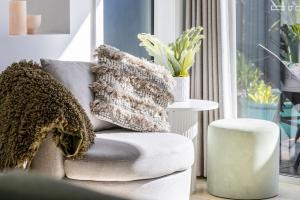 a living room with a chair with a pillow and a table at Sandcastles at the Beach - Linen Supplied & Beds Ready on Arrival in Fingal Bay