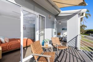 a balcony with a bed and two chairs at Sandcastles at the Beach - Linen Supplied & Beds Ready on Arrival in Fingal Bay
