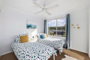 two beds in a room with a window at Sandcastles at the Beach - Linen Supplied & Beds Ready on Arrival in Fingal Bay