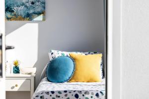 a bedroom with a bed with blue and yellow pillows at Sandcastles at the Beach - Linen Supplied & Beds Ready on Arrival in Fingal Bay