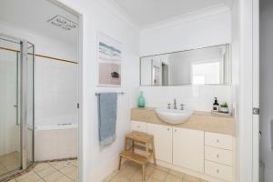 a white bathroom with a sink and a shower at Sandcastles at the Beach - Linen Supplied & Beds Ready on Arrival in Fingal Bay