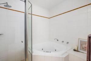 a bathroom with a tub and a glass shower at Sandcastles at the Beach - Linen Supplied & Beds Ready on Arrival in Fingal Bay