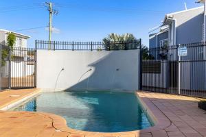 a swimming pool in front of a fence at Sandcastles at the Beach - Linen Supplied & Beds Ready on Arrival in Fingal Bay