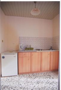 a kitchen with a white refrigerator and wooden cabinets at Stella Studios in Laganas