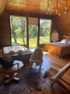 a bedroom with a bed and a bath tub and a bed and a table at Cabana Paradouro da Serra in Cambara do Sul