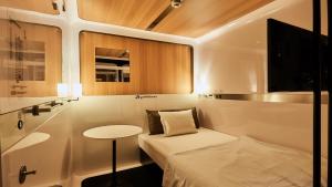 a small room with a bed and a table at First Cabin Nishi Umeda in Osaka