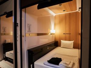 a small bed in a small room with a mirror at First Cabin Nishi Umeda in Osaka