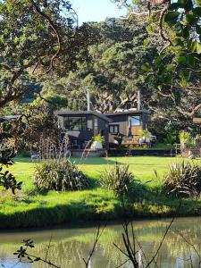 a house on a lawn next to a body of water at Adventurer's Chest - Taiwawe in Hotwater Beach