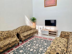 een woonkamer met 2 stoelen en een televisie bij Nasrah Homestay Alor Gajah in Kampong Alor Gajah