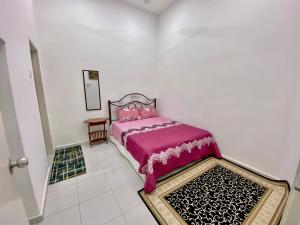 een slaapkamer met een roze bed in een witte kamer bij Nasrah Homestay Alor Gajah in Kampong Alor Gajah