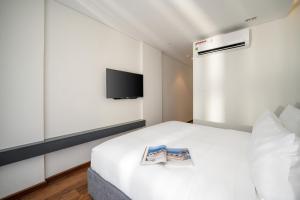 Un dormitorio con una cama blanca con una revista. en Tashi Ocean Hotel & Apartment Da Nang en Da Nang