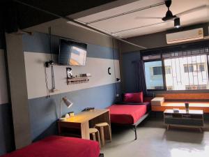 Habitación con 2 camas, mesa y escritorio. en Amity Poshtel en Krabi