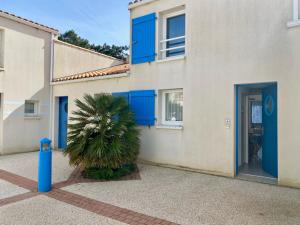 dom z niebieskimi drzwiami i palmą przed nim w obiekcie Pavillon à Longeville-sur-Mer, proche plage, 6 pers, 3 ch, terrasse, parking privé - FR-1-336-135 w mieście Longeville-sur-Mer +12 zdjęć