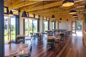 uma sala de jantar com mesas, cadeiras e janelas em Tussock Hill Vineyard Retreats em Christchurch