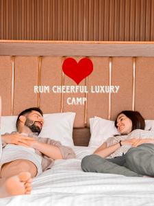 RUM CHEERFUL lUXURY CAMP في وادي رم: رجل وامرأة يستلقيان في سرير
