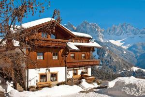 a building in the snow with mountains in the background at Apartments home Niedermunthof, Villnöß in Funes