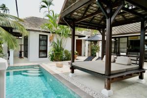 a bed in a villa with a swimming pool at 3 Bedroom Seaview Villa Haven on Beachfront Resort in Koh Samui 