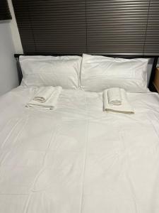 Una cama blanca con dos toallas encima. en A lovely studio in Kings Meadows, en Kings Meadows