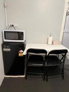 a small table and chairs with a microwave on top of a refrigerator at A lovely studio in Kings Meadows in Kings Meadows