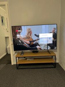 a large flat screen tv with a music video on it at A lovely studio in Kings Meadows in Kings Meadows
