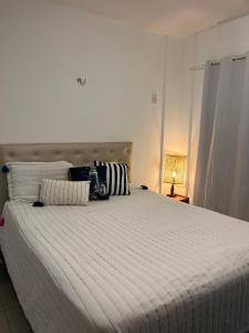 ein großes weißes Bett in einem Zimmer mit einer Lampe in der Unterkunft Chalé Paraíso -Maracajaú 4- Casa 38 - Beira-mar in Maxaranguape + 27 Fotos