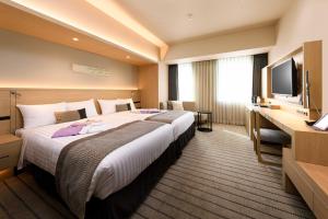 a hotel room with a large bed and a flat screen tv at HOTEL OLE INN in Shizuoka