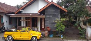een gele auto geparkeerd voor een huis bij Homestay dwi prasetyo in Kembanglimus