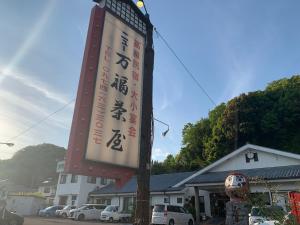 un panneau sur un poteau devant d'un bâtiment dans l'établissement 民宿ニュー万福茶屋, à Taketa