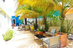 een patio met stoelen, tafels en palmbomen bij Aqua Viva Suites in Kralendijk