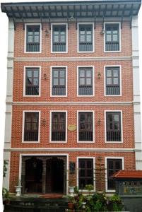 - un grand bâtiment en briques rouges avec des fenêtres blanches dans l'établissement Kaji Chen, The Tourist Accommodation, à Pātan