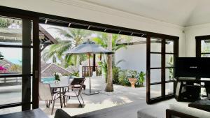 3 Bedroom Seaview Villa Halo on Beachfront Resort في كوه ساموي: غرفة معيشة مع طاولة ومظلة