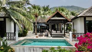 a villa with a swimming pool in front of a house at 3 Bedroom Seaview Villa Halo on Beachfront Resort in Koh Samui 