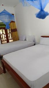 duas camas num quarto com guarda-sóis azuis na parede em Pranu House em Nilaveli