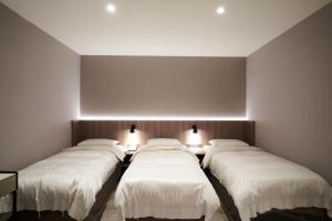 a row of four beds in a room with lights at Yung An Business Hotel in Dounan