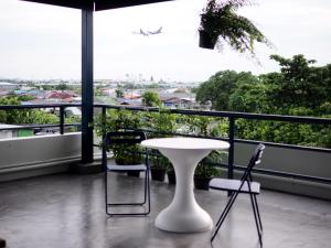 - Balcón con mesa blanca y 2 sillas en Yam Yen Hostel, en Lat Krabang