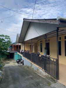 a yellow house with a porch and a balcony at SPOT ON 92544 Senja Homestay in Balikpapan