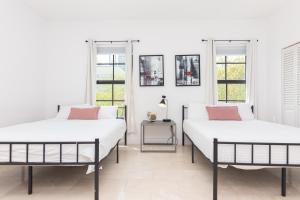 2 camas en una habitación con paredes y ventanas blancas en Miami Downtown Modern Apartment - 5 minutes to Wynwood - 10 minutes to South Beach, en Miami