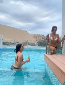 two women sitting in the water in a swimming pool at Hotel Nebai in Ica