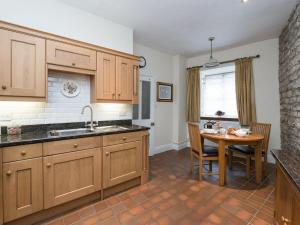 uma cozinha com armários de madeira, uma mesa e uma janela em The Counting House em Wirksworth