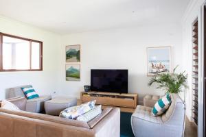 a living room with two couches and a flat screen tv at Casa De Palmeras in Casuarina