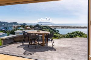 eine Terrasse mit Tisch und Stühlen auf einem Deck in der Unterkunft Blue Skies Sunrise - Mangawhai Heads Holiday Home in Mangawhai
