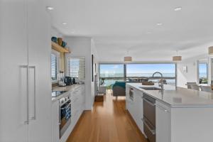 eine Küche mit weißen Arbeitsflächen und einem großen Fenster in der Unterkunft Blue Skies Sunrise - Mangawhai Heads Holiday Home in Mangawhai