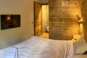 1 dormitorio con cama blanca y pared de madera en Comodità e natura, en Courmayeur