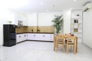 a kitchen with white cabinets and a table and chairs at Thành Vinh Hotel in Ho Chi Minh City